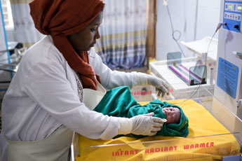 Doctor places infant in radiant warmer.