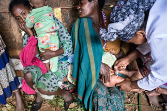 Mothers holding infants who are receiving vaccinations.