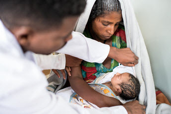 Mother holding an infant during an examination.